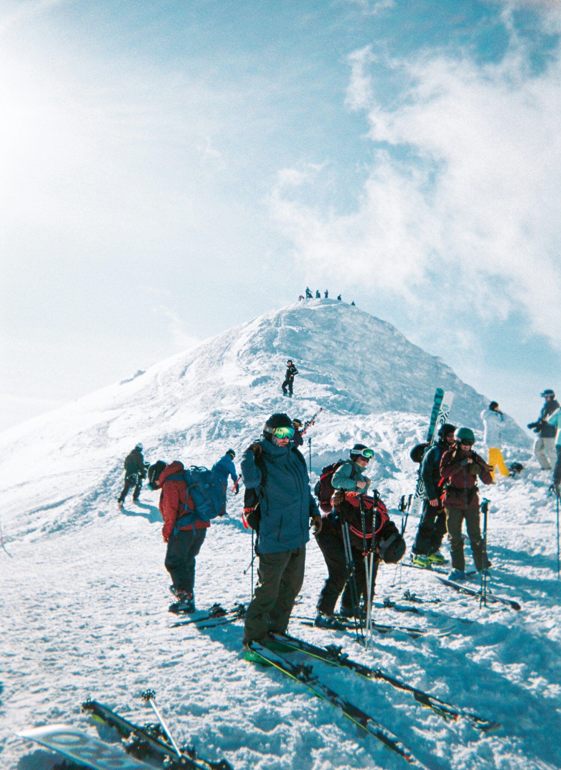 Skiers gearing up at the summit of Mount Yotei, Hokkaido with bright winter sun and fresh powder, showcasing Japan’s top ski terrain.