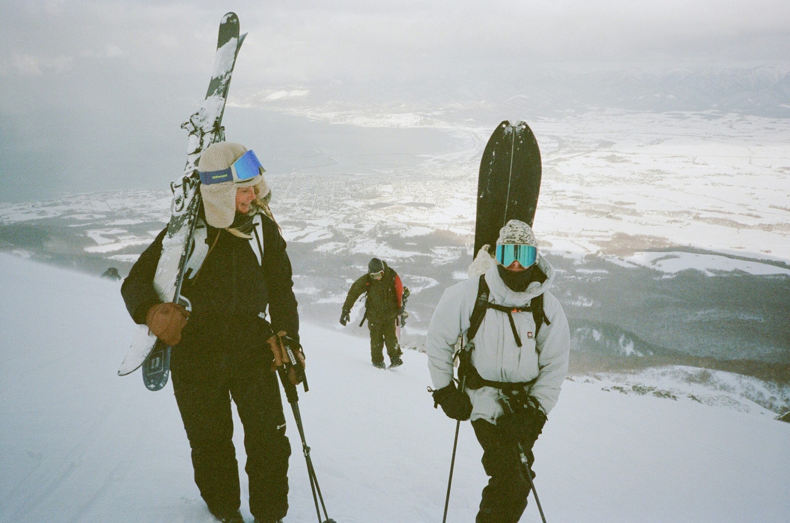Group of skiers climbing a snowy mountain with panoramic views over Niseko, Japan—ideal for backcountry skiing and alpine adventure.