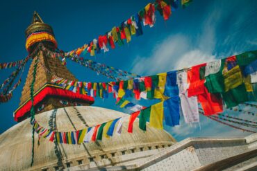 Boudhanath Stupa's golden spire and all-seeing eyes framed by colourful Tibetan prayer flags