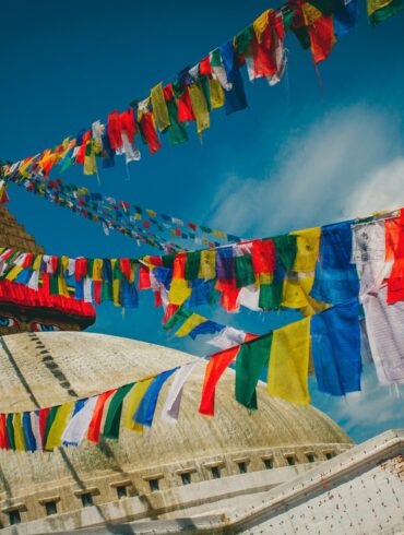 Boudhanath Stupa's golden spire and all-seeing eyes framed by colourful Tibetan prayer flags