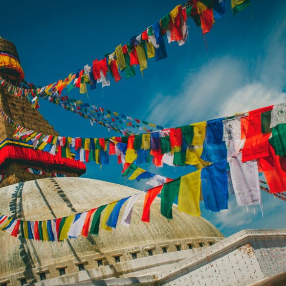 Boudhanath Stupa's golden spire and all-seeing eyes framed by colourful Tibetan prayer flags