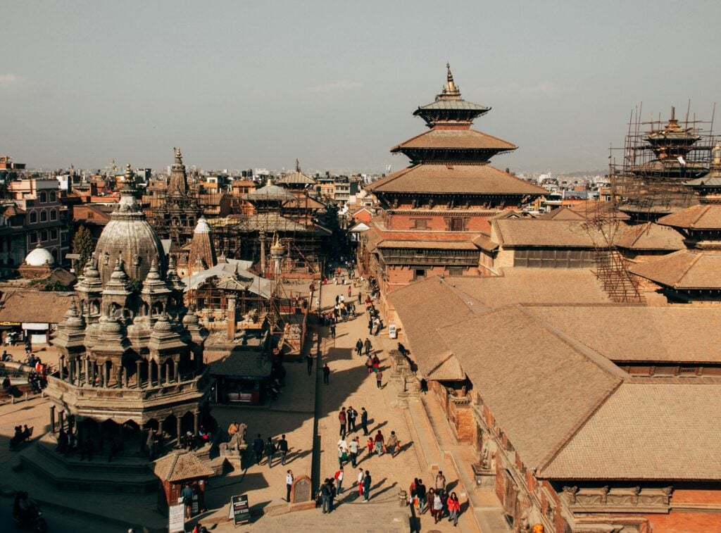 Aerial view of Patan Durbar Square's pagoda temples and stone shikhara spires with visitors walking below
