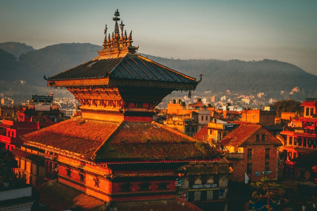 Golden hour light on a pagoda-roofed temple overlooking rooftops in the Kathmandu Valley, Nepal