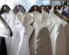 A set of light colored suit jackets hung on display.