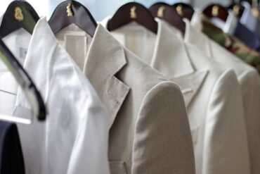 A set of light colored suit jackets hung on display.