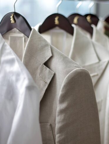 A set of light colored suit jackets hung on display.