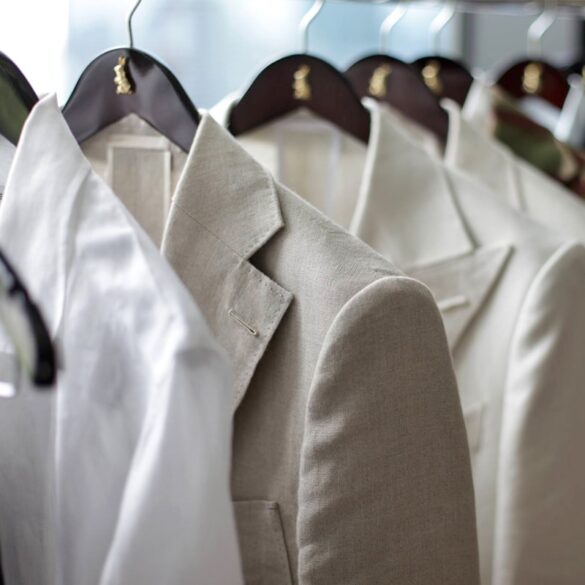 A set of light colored suit jackets hung on display.
