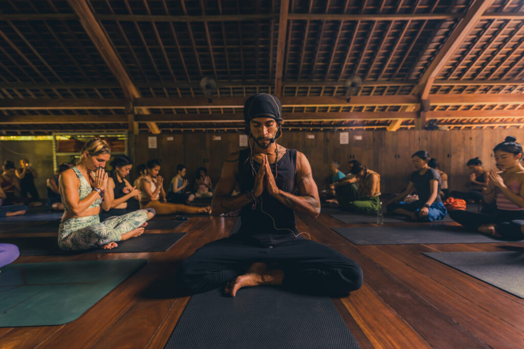 A teacher and students in seated meditation during a yoga class at The Yoga Barn, Ubud, Bali