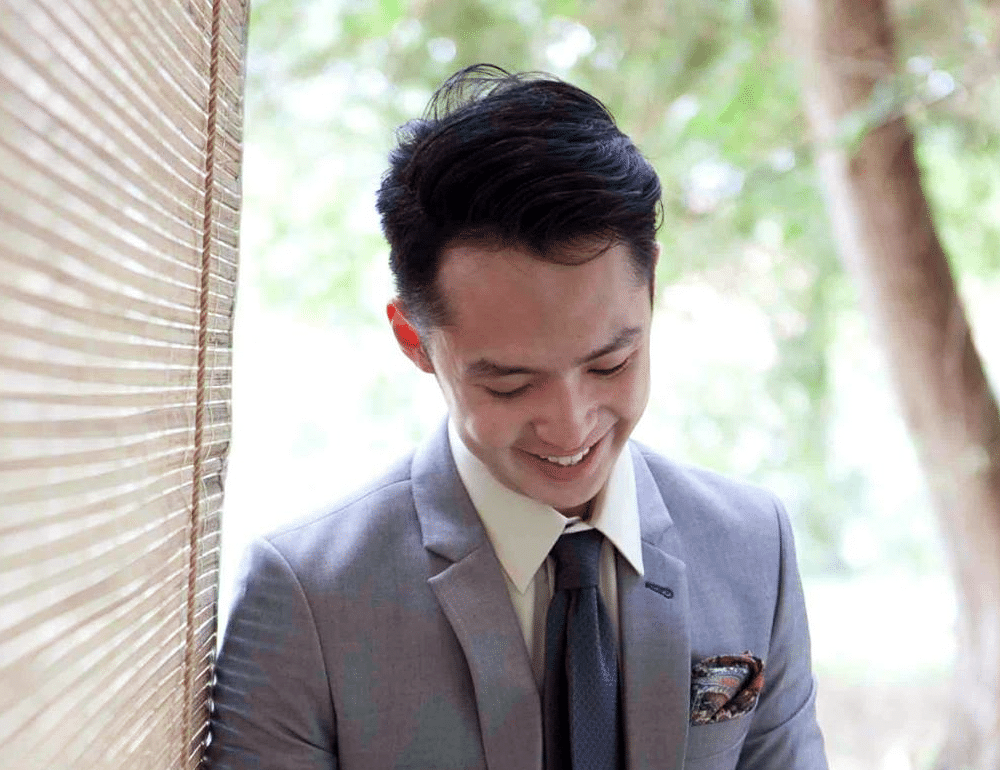 An Asian young adult man dressed in a grey suit