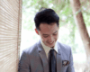 An Asian young adult man dressed in a grey suit