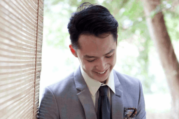 An Asian young adult man dressed in a grey suit