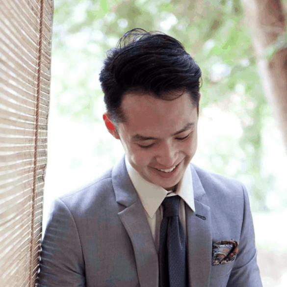 An Asian young adult man dressed in a grey suit