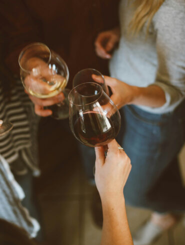 Friends clinking glasses of red and white wine at a casual bar gathering in Singapore