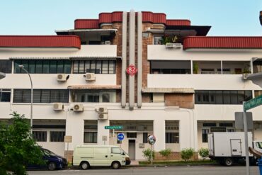 Art Deco pre-war shophouse block on Tiong Poh Road in Tiong Bahru, Singapore, with curved red roof and street-level cafes.