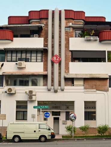 Art Deco pre-war shophouse block on Tiong Poh Road in Tiong Bahru, Singapore, with curved red roof and street-level cafes.
