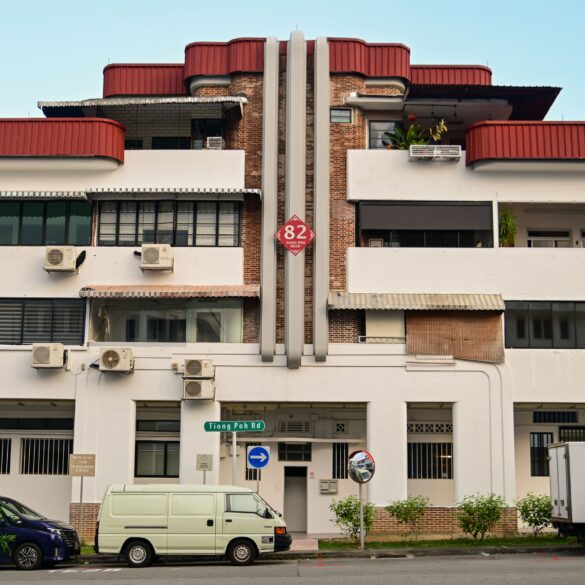 Art Deco pre-war shophouse block on Tiong Poh Road in Tiong Bahru, Singapore, with curved red roof and street-level cafes.
