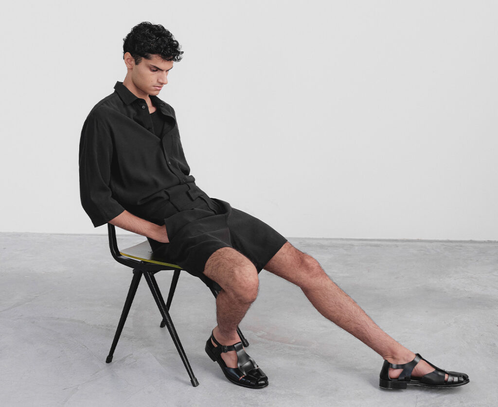In Good Company menswear look featuring a black short-sleeve shirt, tailored shorts, and leather sandals