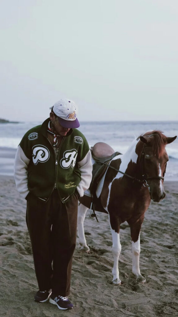 Pharaoh's Horses varsity jacket worn on a beach alongside a horse