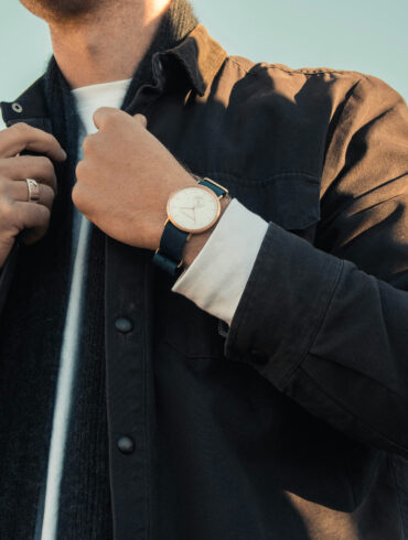 Man adjusting his jacket collar, wearing layered outerwear with a watch