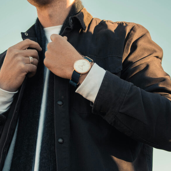 Man adjusting his jacket collar, wearing layered outerwear with a watch