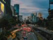 Heavy traffic on a multi-lane road in Singapore's CBD at dusk, with car light trails and the city skyline in the background