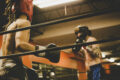 Two boxers sparring in headgear and gloves inside a boxing ring at a gymTwo boxers sparring in headgear and gloves inside a boxing ring at a gym