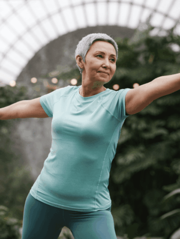 An elderly woman practising self-healing technique like yoga in the park