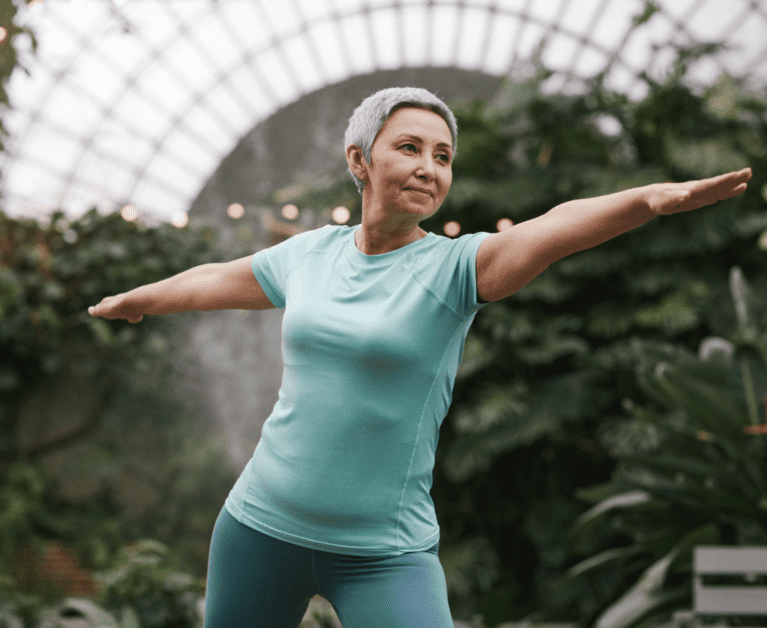 An elderly woman practising self-healing technique like yoga in the park