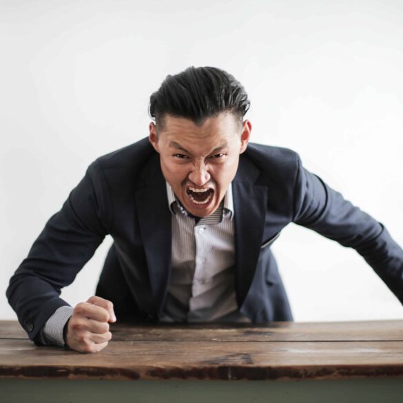 A man wearing formal suit yelling and pounding the table