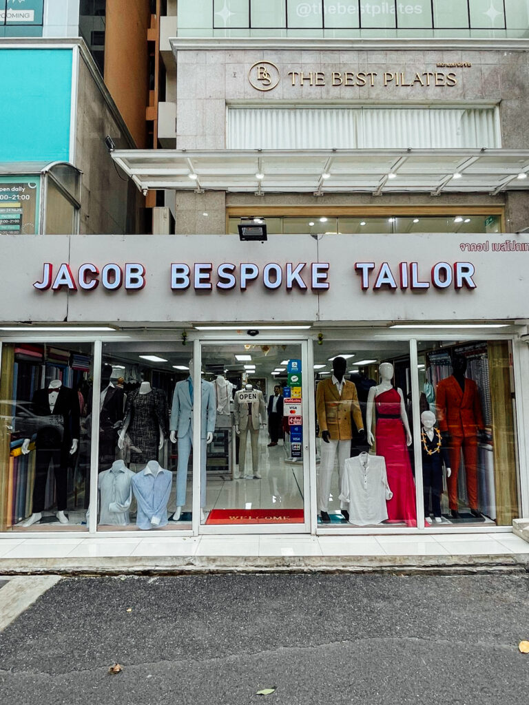 Jacob Bespoke Tailor storefront off Sukhumvit Soi 30/1 in Bangkok, with suits, shirts and a dress displayed in the shop window
