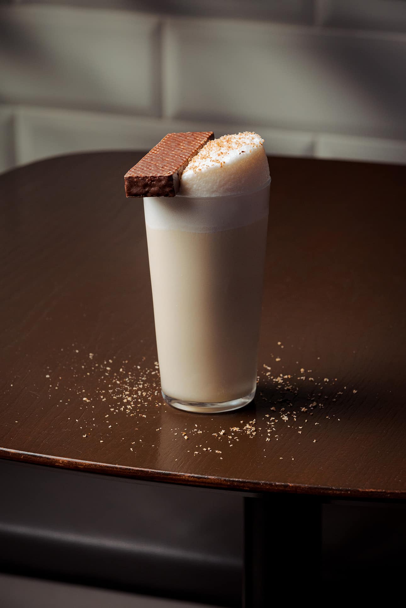 Signature cocktail from Nutmeg & Clove Singapore served in a highball glass with creamy foam topping, garnished with a chocolate wafer and grated nutmeg — modern Singaporean bar blending local flavours with creative mixology.