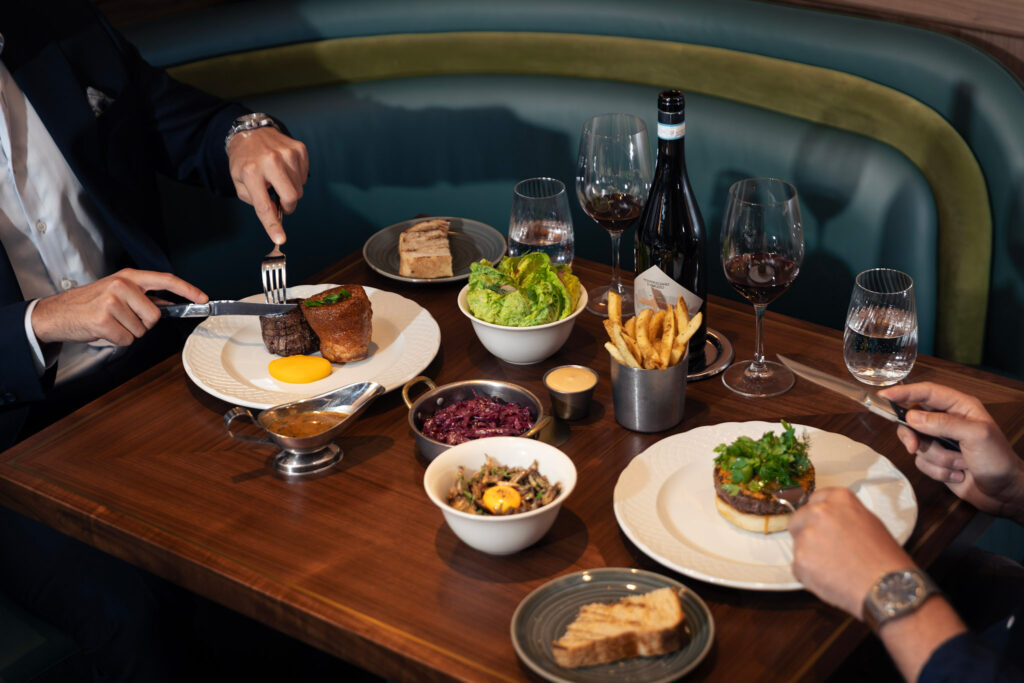 Executive set lunch at Stags Head Steakhouse, Pan Pacific Singapore, with two diners sharing grilled beef tenderloin, Yorkshire pudding, wagyu burger, fries and red wine