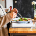 A diner enjoying a salad with a glass of white wine at a restaurant table, representing the best set lunches in Singapore