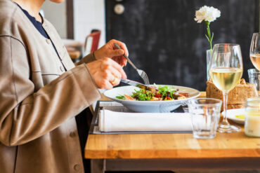 A diner enjoying a salad with a glass of white wine at a restaurant table, representing the best set lunches in Singapore