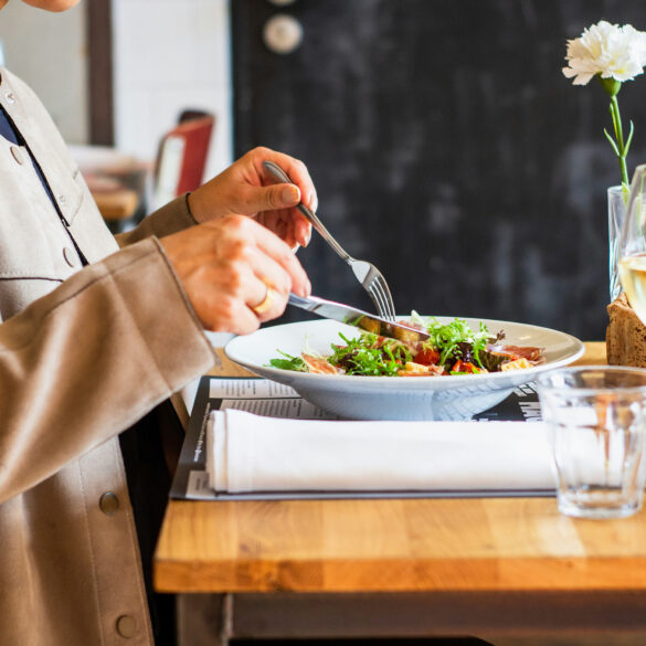 A diner enjoying a salad with a glass of white wine at a restaurant table, representing the best set lunches in Singapore