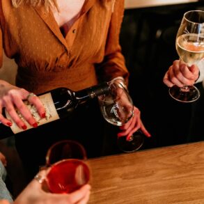 Group of friends pouring and enjoying red and white wine at a bar during happy hour in Singapore, showcasing casual nightlife and social drinking culture.