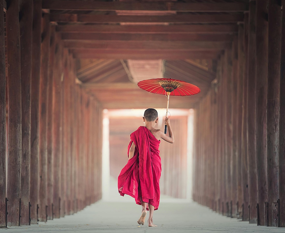 Boy Walking Between Wooden Frame While Holding Umbrella