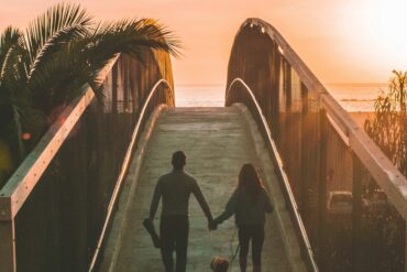 couple and their dog walking into sunset