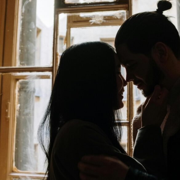 a photo of a man and woman kissing the near the window.