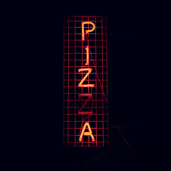 An orange neon sign displaying the word "Pizza"