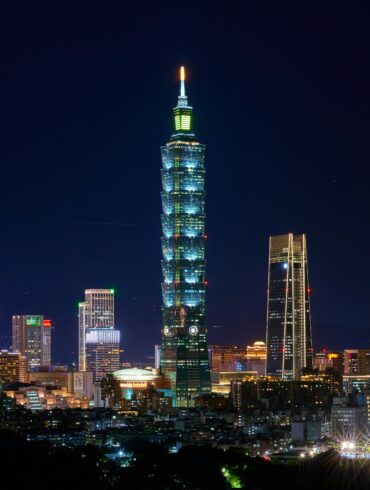 Free Illuminated Taipei 101 and city skyline at night showcasing modern urban architecture. Stock Photo