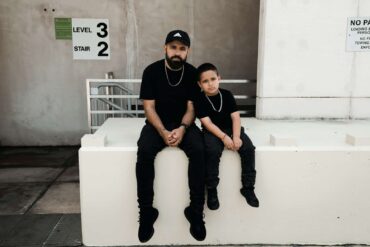 father and son sitting on a ledge, both wearing black.