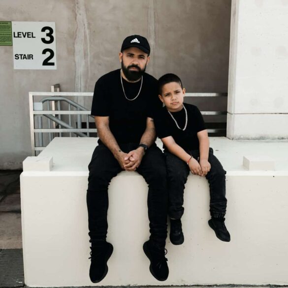 father and son sitting on a ledge, both wearing black.