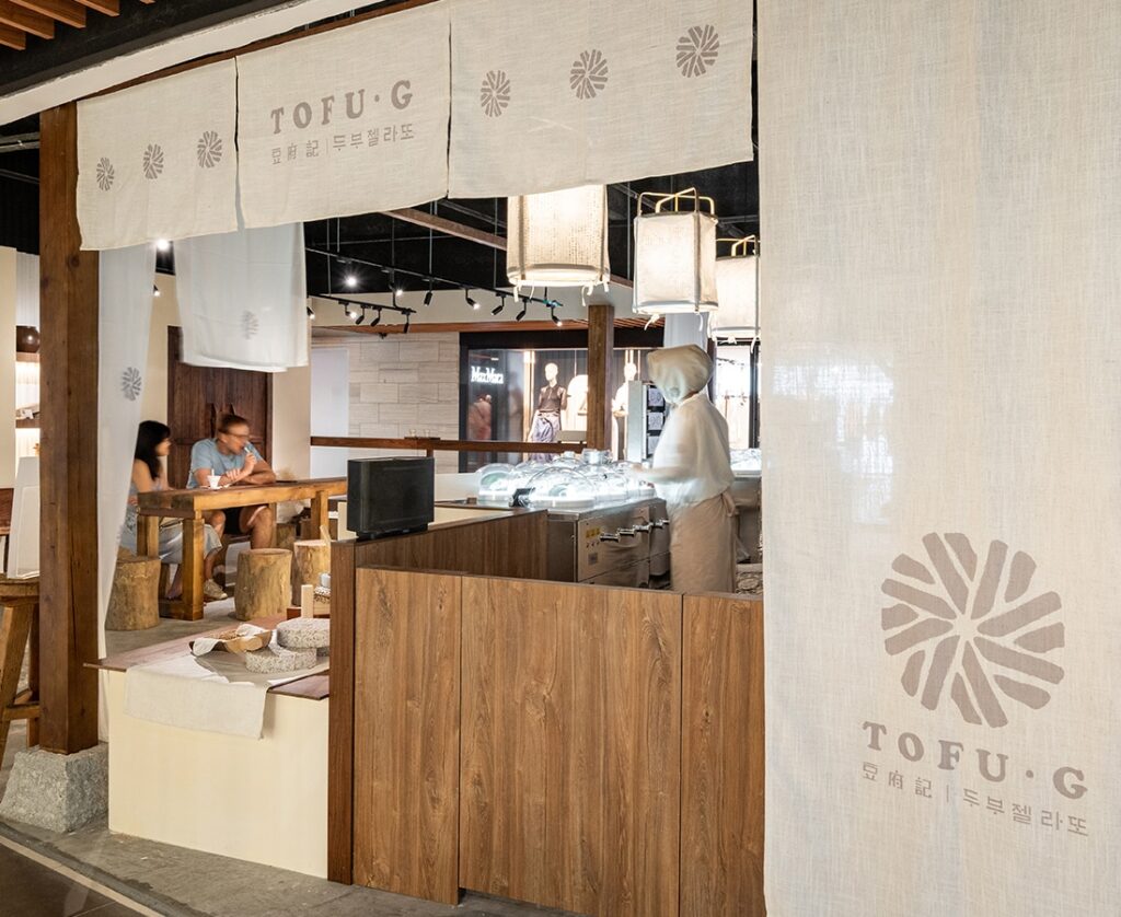 Minimalist wood-and-linen interior of TOFU G at Mandarin Gallery, Singapore’s first tofu gelato concept serving dairy-free frozen desserts.