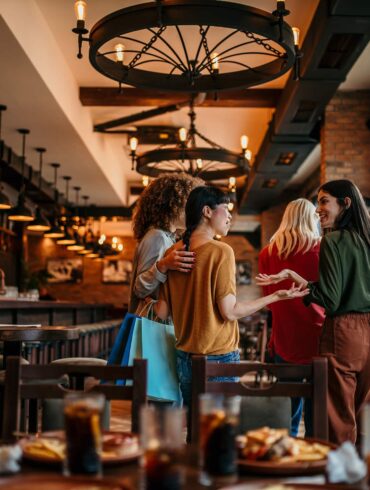 Group of women entering a modern restaurant in Singapore, smiling and chatting after shopping – August 2025 dining scene.