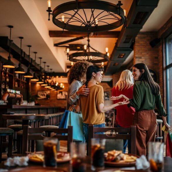 Group of women entering a modern restaurant in Singapore, smiling and chatting after shopping – August 2025 dining scene.