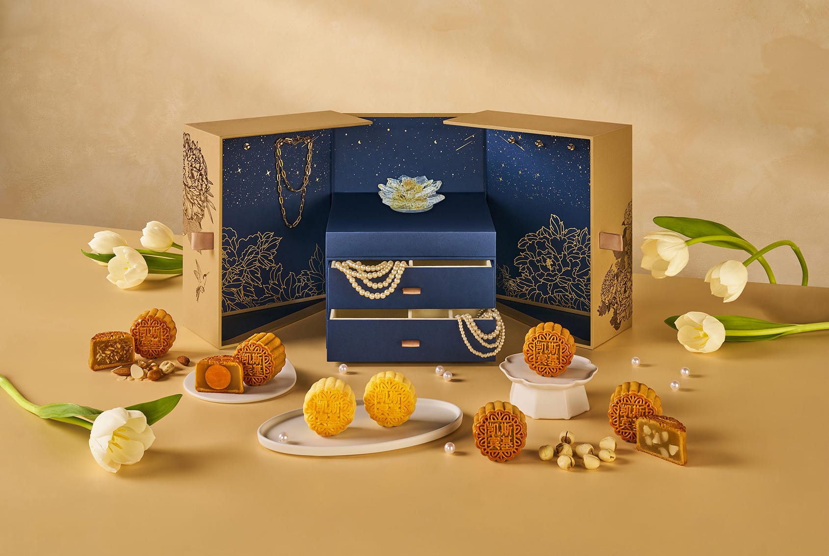 Capitol Kempinski’s luxurious mooncake gift box in navy and gold, styled like a musical jewellery chest with elegant baked and snowskin mooncakes surrounded by tulips and pearl accents.