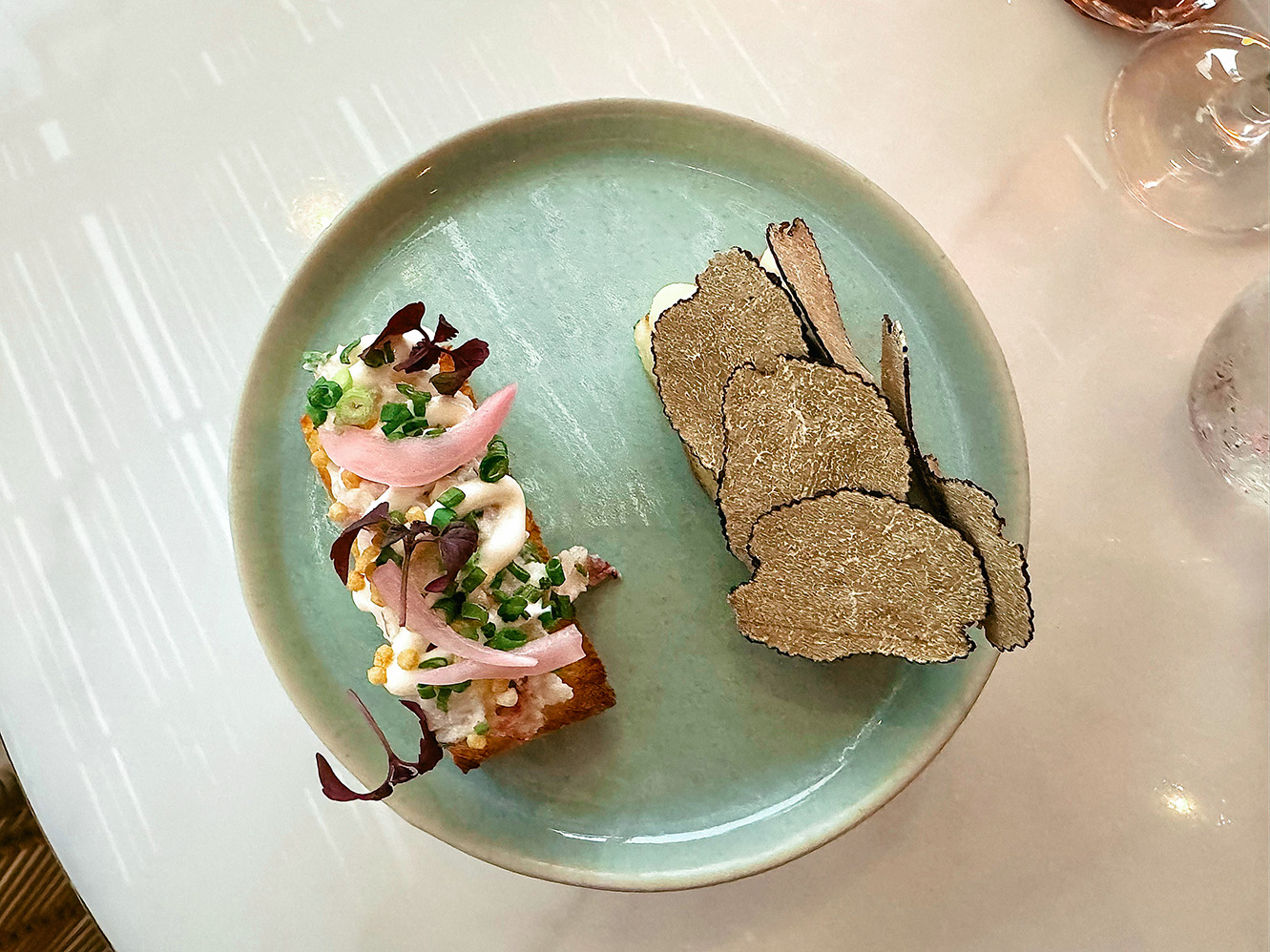 Signature truffle toast at Pastel Bangkok rooftop restaurant, topped with shaved black truffles, pickled onions, herbs, and creamy spread for a Mediterranean flavour.