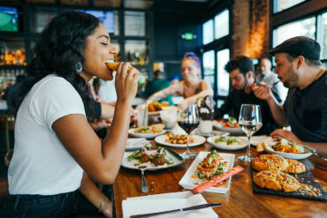 Group of friends enjoying diverse dishes at a restaurant in Singapore, featuring shared plates, wine, and dessert during a casual dining experience.