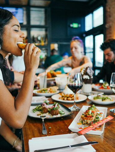 Group of friends enjoying diverse dishes at a restaurant in Singapore, featuring shared plates, wine, and dessert during a casual dining experience.